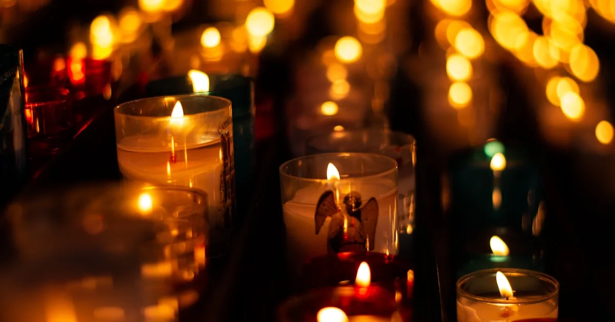 Velas acesas enfileiradas dentro de uma igreja católica iluminando o ambiente de oração silenciosa.