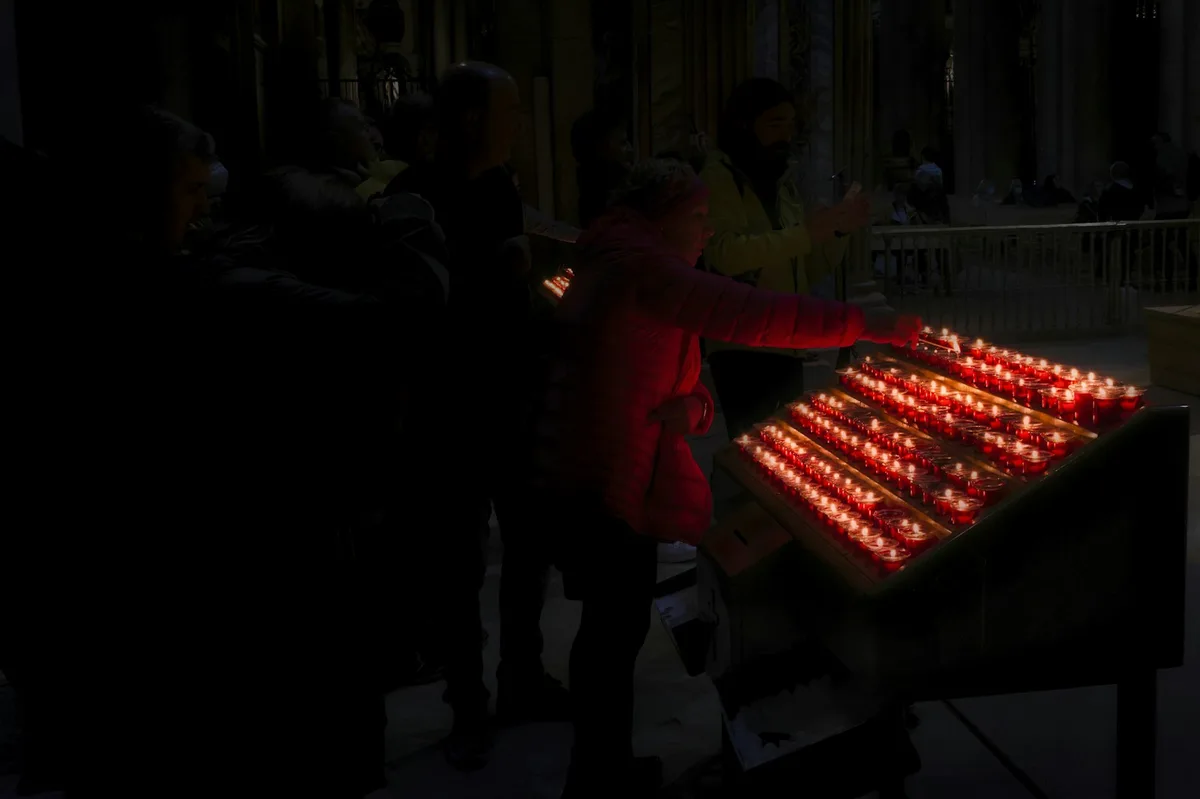 Velas votivas acesas em igreja, simbolizando a oração pelos fiéis defuntos e a comunhão dos santos